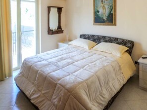 A bedroom with a large bed, a nightstand, a mirror, and a painting on the wall.
