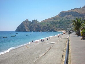 A beach with boats, people, and a rocky hill in the background. - Dolce Casa n 41 (Savoca)