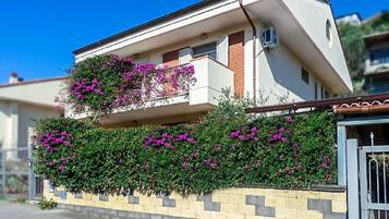 Stunning two-story building with a flat roof and a balcony featuring a lush garden.