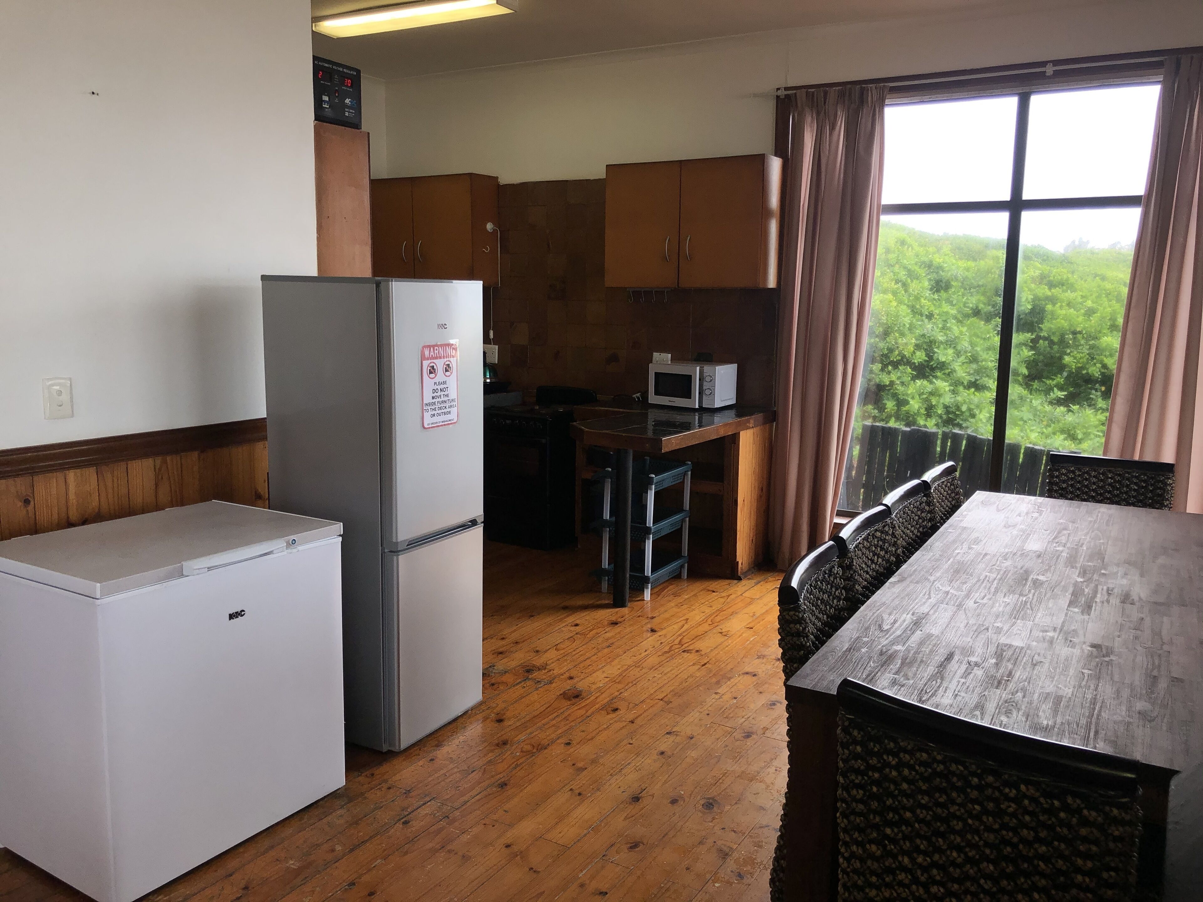 A compact kitchen with a refrigerator, microwave, and wooden cabinets.