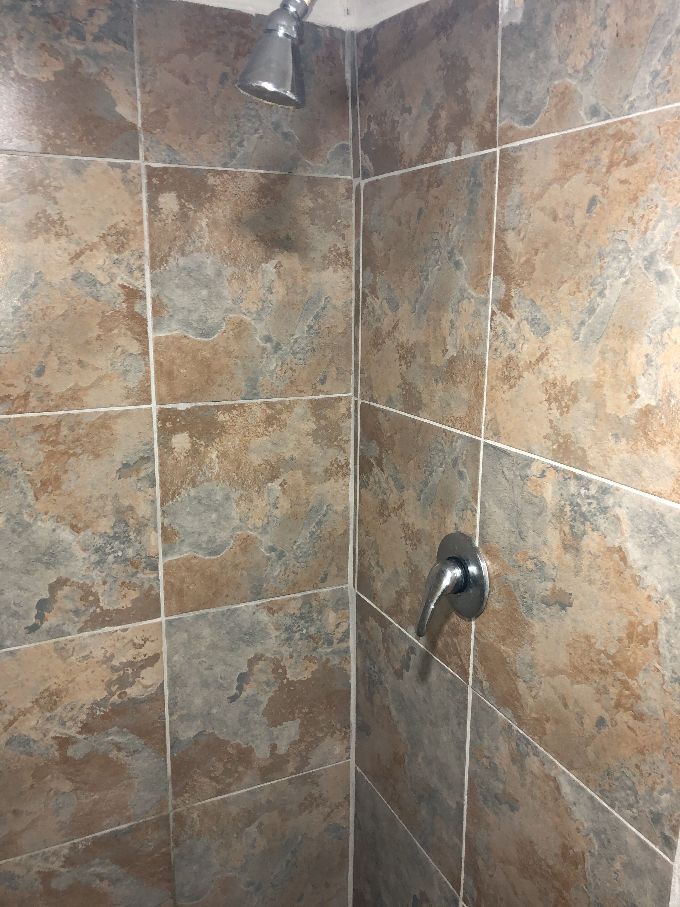 A corner of a bathroom with tiled walls and a showerhead.