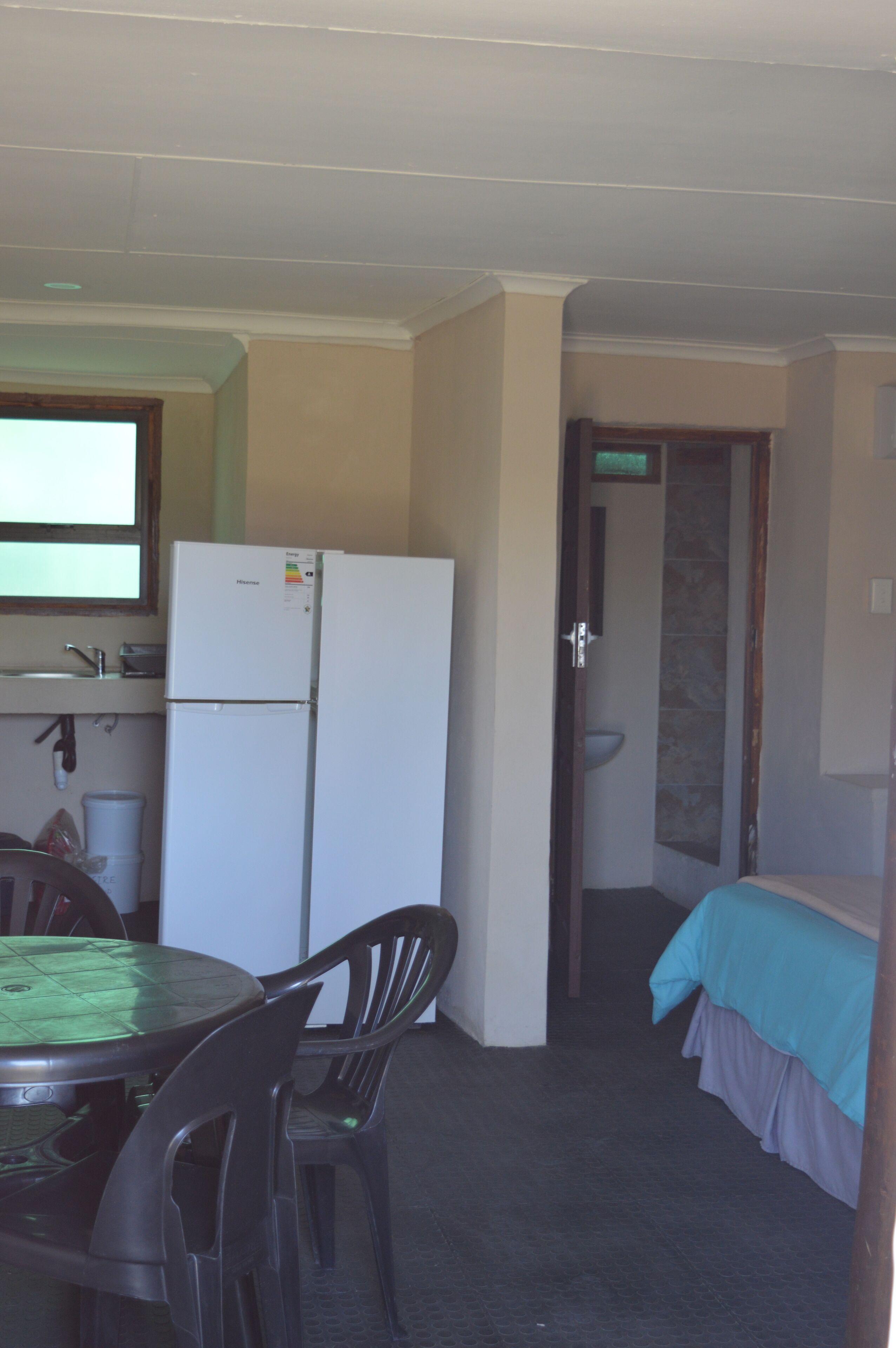 Habitación compacta con kitchenette, zona de comedor con mesa y sillas, y cama con cubierta azul.