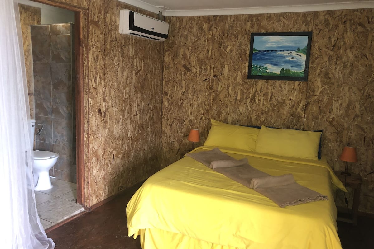 Quarto com cama, quadro, ar condicionado e chuveiro.