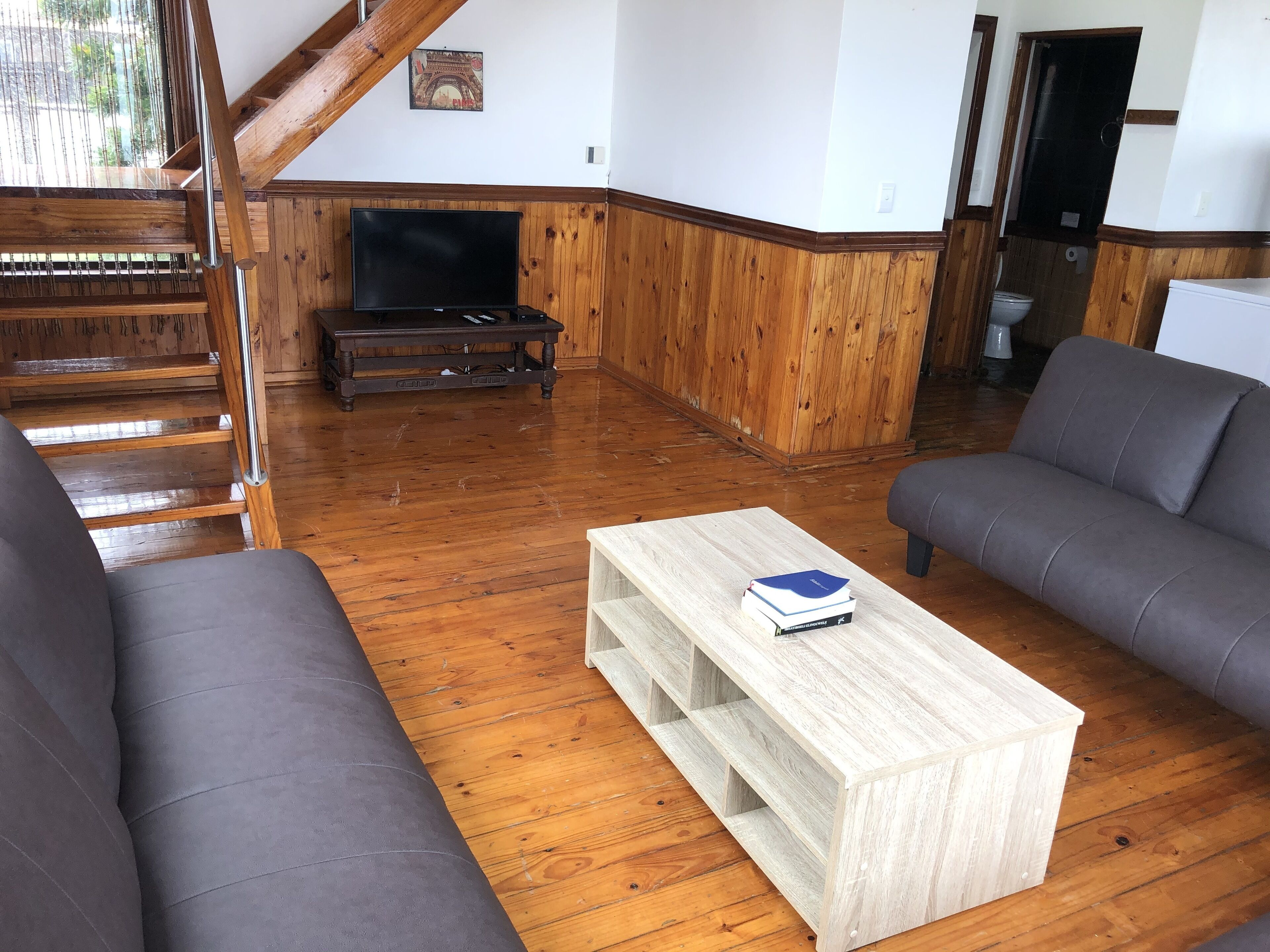 Een woonkamer met houten vloeren, een televisie, een bank en een salontafel.