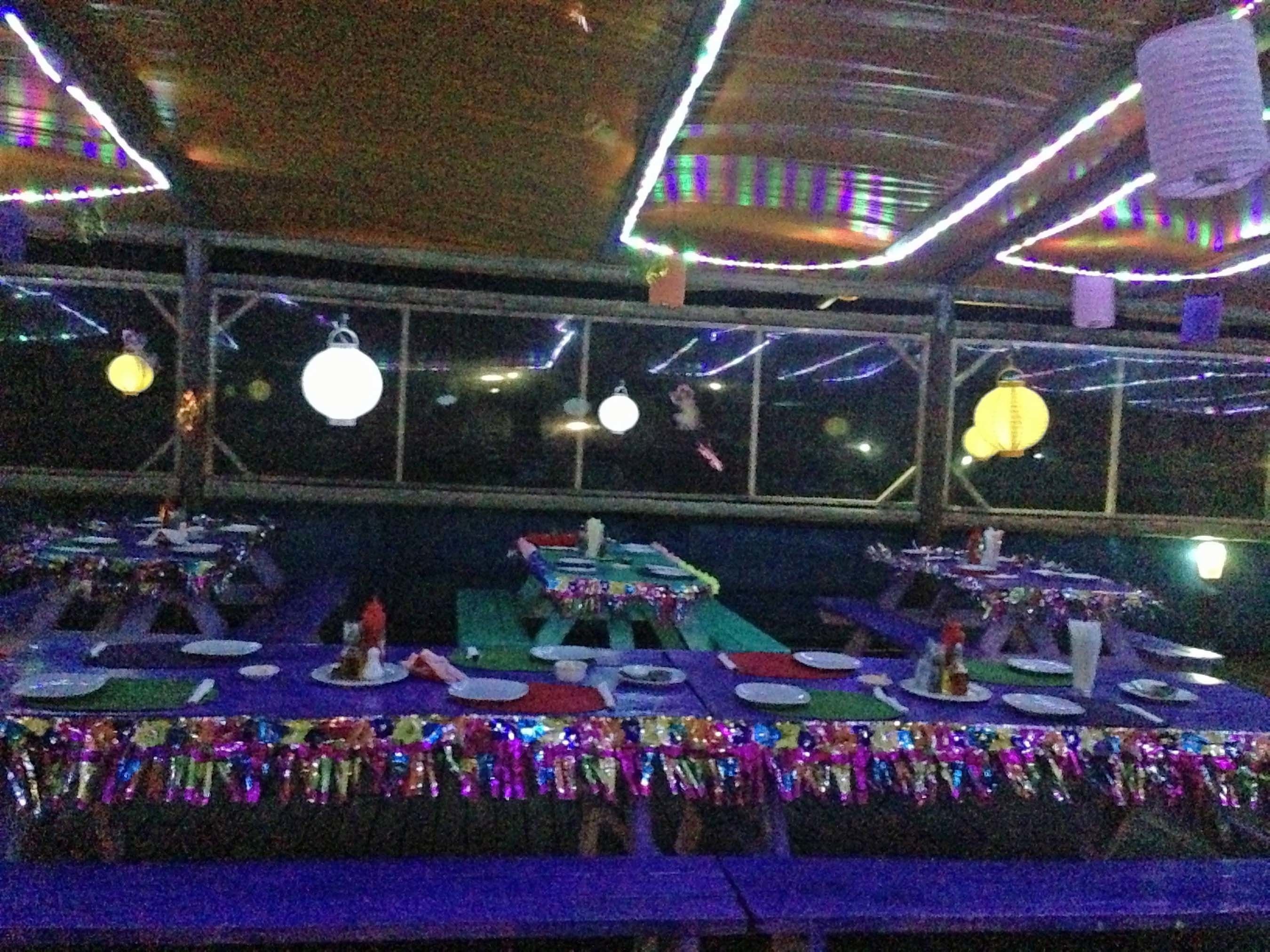 Een restaurant met gedekte tafels, verlichting erboven en uitzicht door grote ramen.