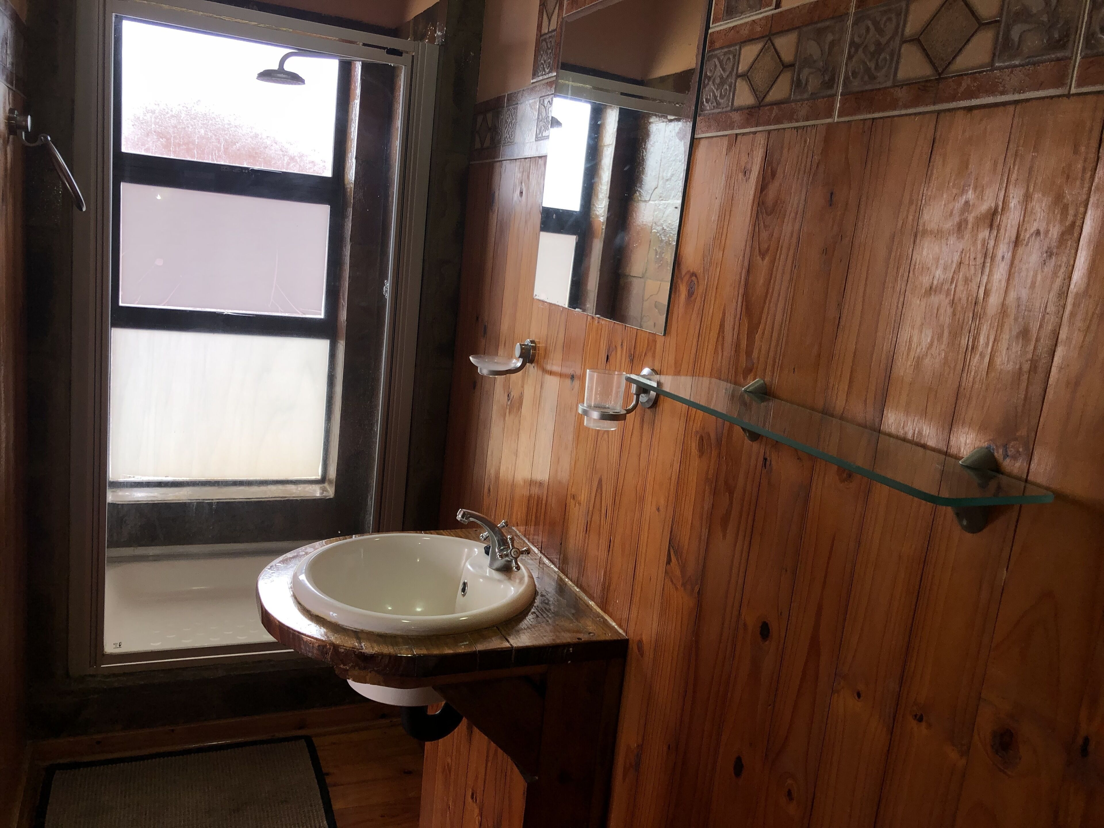 Un bany de fusta amb un lavabo, un mirall i una finestra.