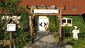 A wooden archway with a sign reading "Herzlich Willkommen" leading to a building with a red roof. - Gasthaus Zum Rethberg (Lübstorf)