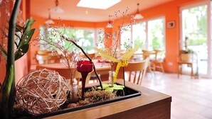 A dining area with a wooden table, chairs, and a decorative centerpiece featuring plants and a yellow object. - Gasthaus Zum Rethberg (Lübstorf)