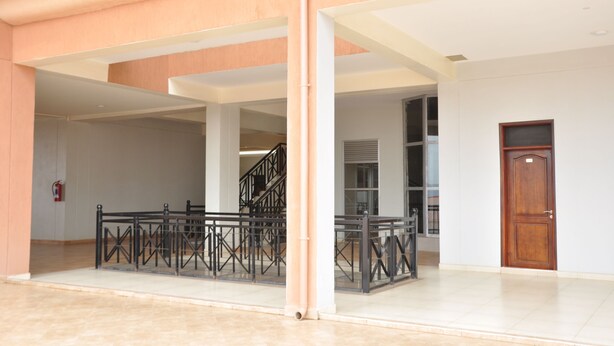Un hall d’entrée spacieux avec un escalier, un extincteur et une porte en bois.