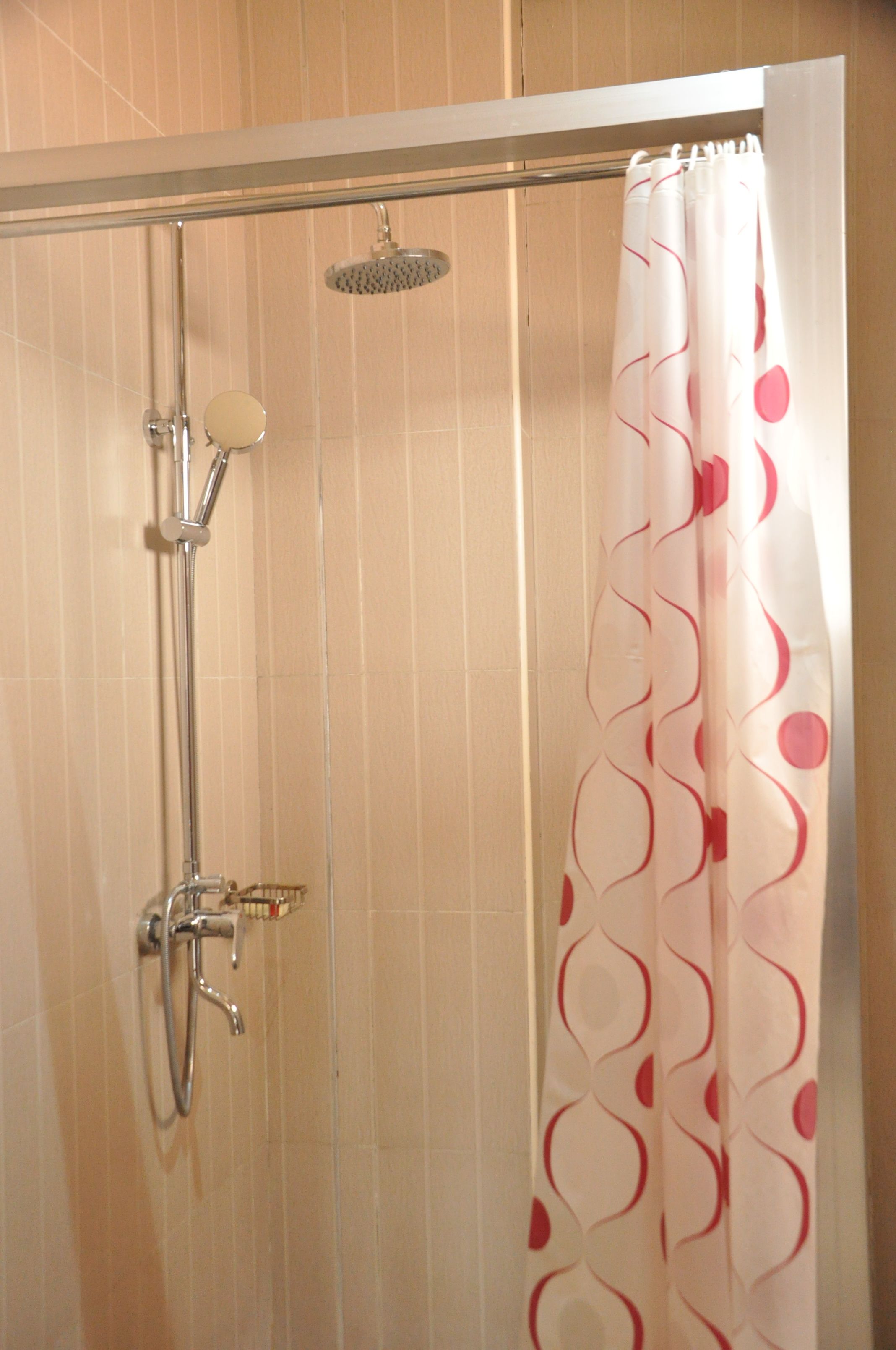 A shower with a handheld showerhead and a wall-mounted faucet.