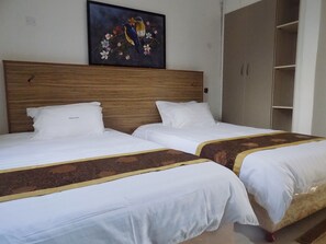 A hotel room with two beds, a wooden headboard, a painting of birds and flowers, and a wardrobe.