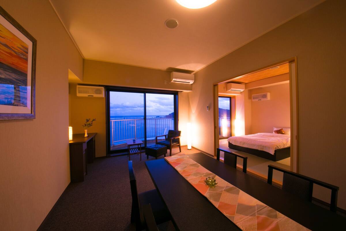 Quarto de hotel com varanda, cama, escrivaninha e cadeira.