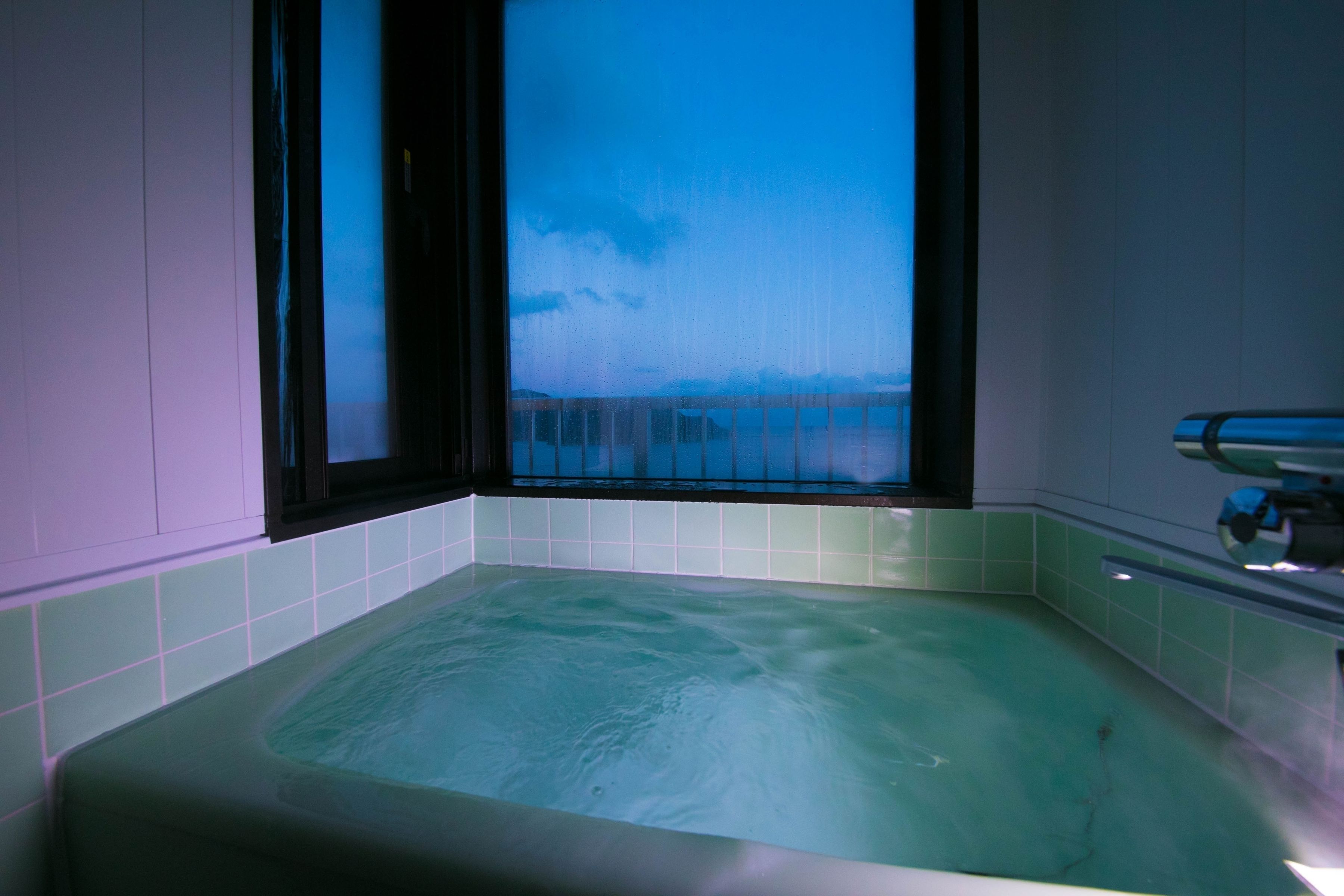Una bañera con vistas al cielo y nubes a través de una ventana.