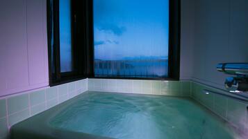 Una bañera con vistas al cielo y nubes a través de una ventana.