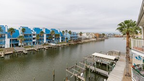 A marina with docked boats, a waterway, and buildings with blue and white exteriors. - Spacious 2br 2bath condo! On the canal with a boat lift! (Corpus Christi)