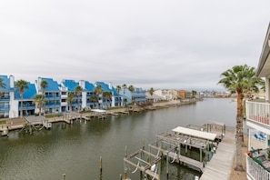 Un port de plaisance avec des bateaux amarrés, une voie navigable et des bâtiments aux façades bleues et blanches.