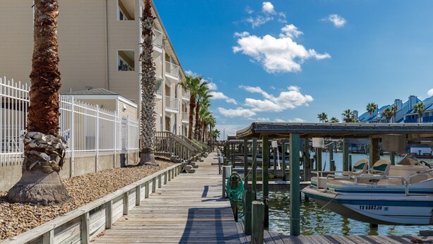 A wooden boardwalk leading to a marina with boats docked. - Spacious 2br 2bath condo! On the canal with a boat lift! (Corpus Christi)