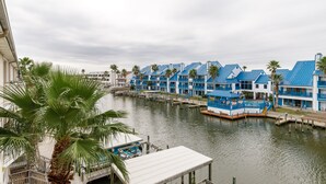 A waterfront hotel with blue-roofed buildings, a dock, and palm trees. - Spacious 2br 2bath condo! On the canal with a boat lift! (Corpus Christi)