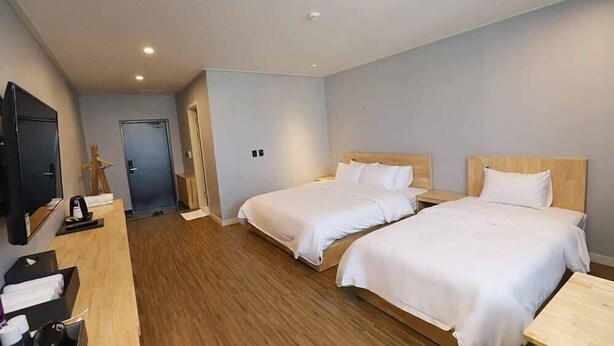 Habitación de hotel con dos camas, televisión y piso de madera.