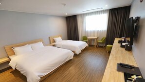 Habitación de hotel con dos camas, un escritorio, una silla, un televisor y una ventana con cortinas.