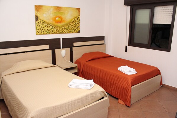 A hotel room with two beds, one larger and one smaller, both with neatly folded white towels on them. - Terra del Sole B&B (Vittoria)