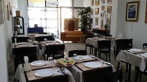 A restaurant with tables set for dining, a sofa, and artwork on the walls. - Terra del Sole B&B (Vittoria)