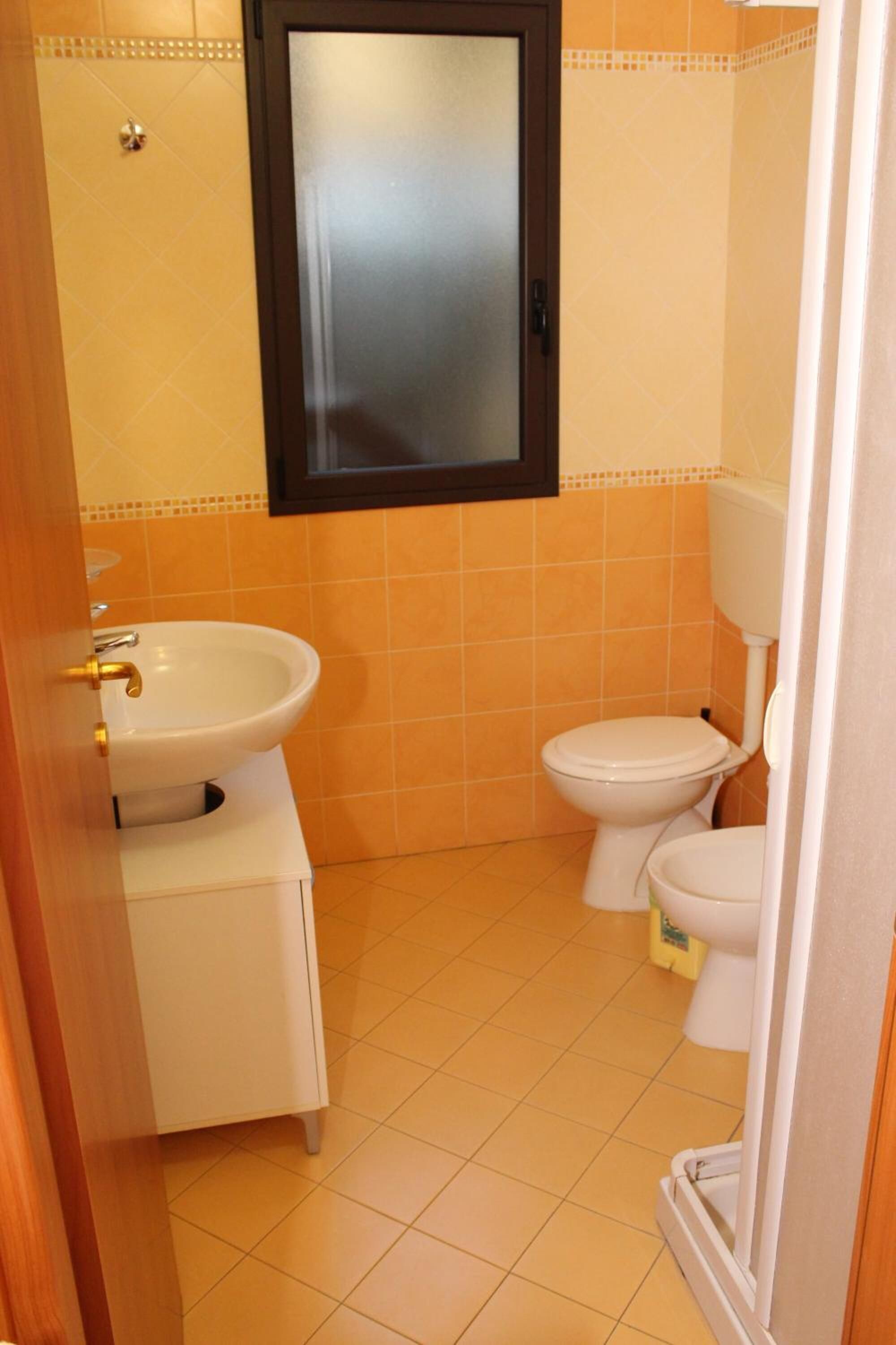 A small bathroom with a white sink, toilet, and a mirror above the sink.
