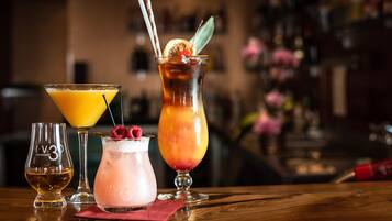 A bar setting with three drinks in different glasses, a small bottle, and a red napkin on the table.