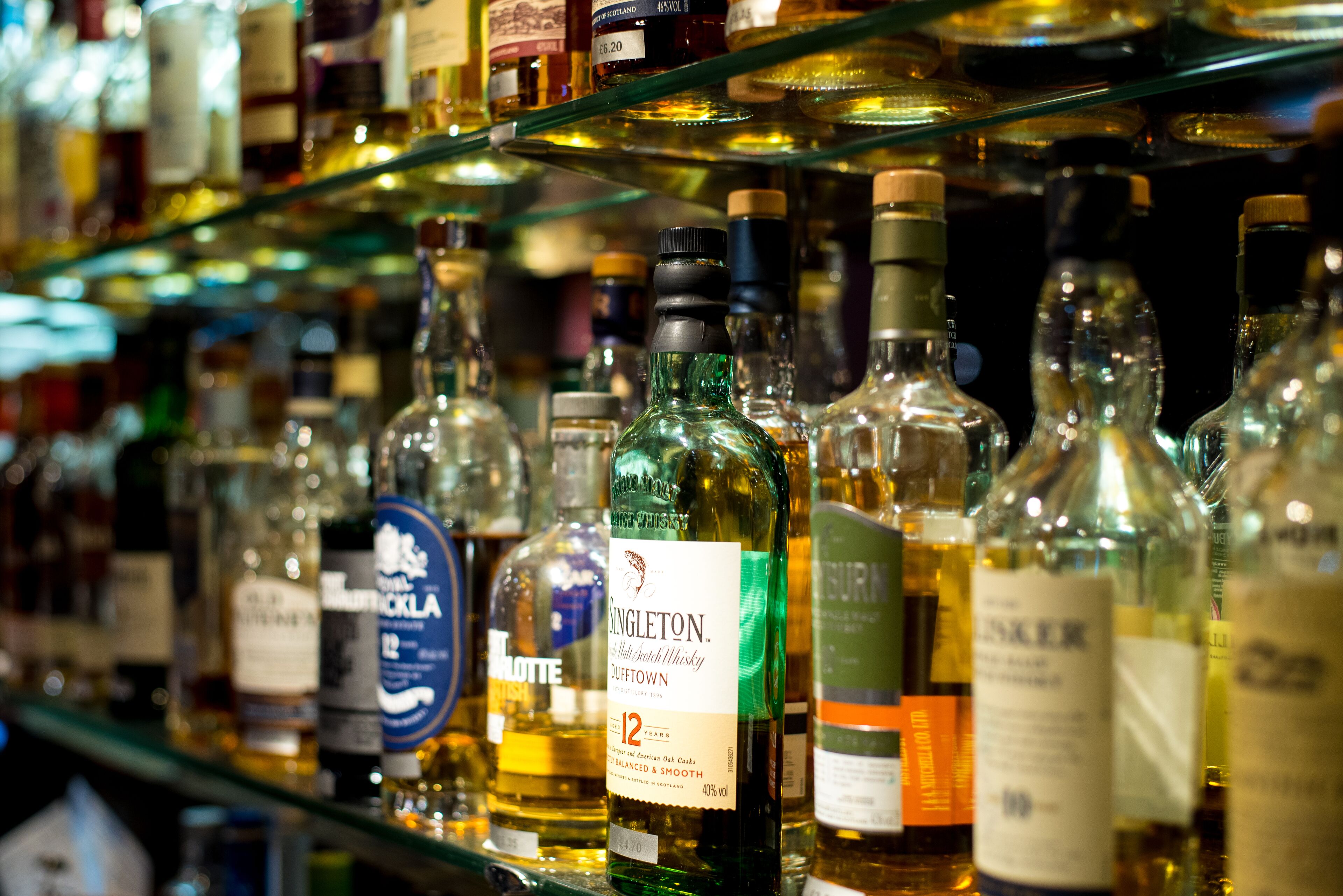 Erilaisia väkeviä alkoholijuomia sisältäviä pulloja hyllyillä kaupassa.