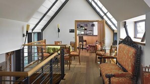 Une pièce de style « loft », avec un plafond haut, un escalier, un coin repas et une cuisine visible à travers une porte ouverte.