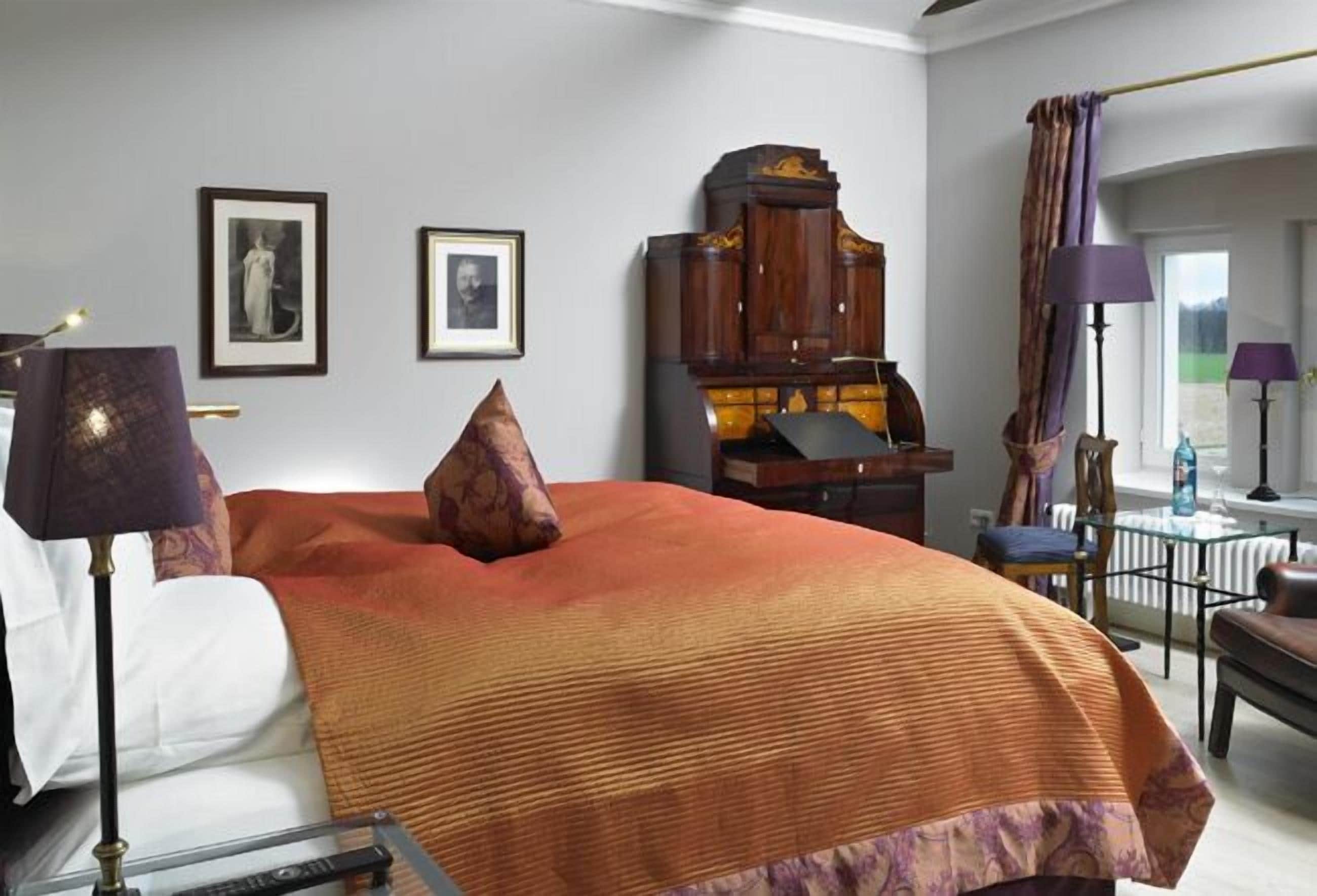 A hotel room with a large bed, a wooden cabinet, a desk, and a chair.