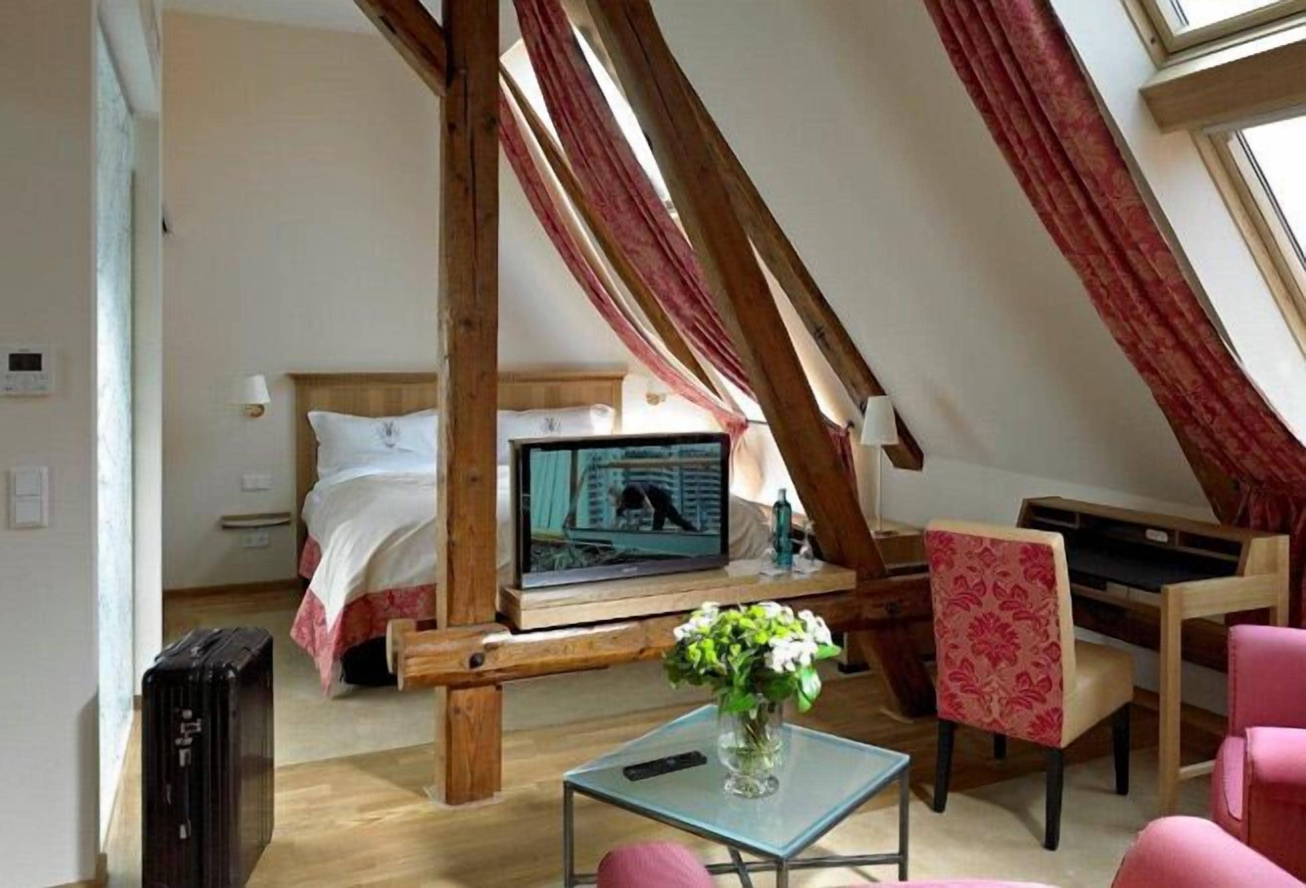 Een slaapkamer met een bed, een televisie, een bureau en een stoel.
