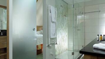 A modern bathroom with a glass shower enclosure, a visible towel rack, and a sink area with toiletries.