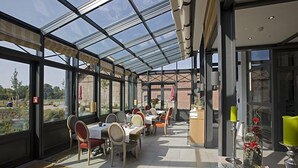 Un espace de restauration intérieur avec des tables et des chaises, un plafond en verre et une vue sur l’extérieur.