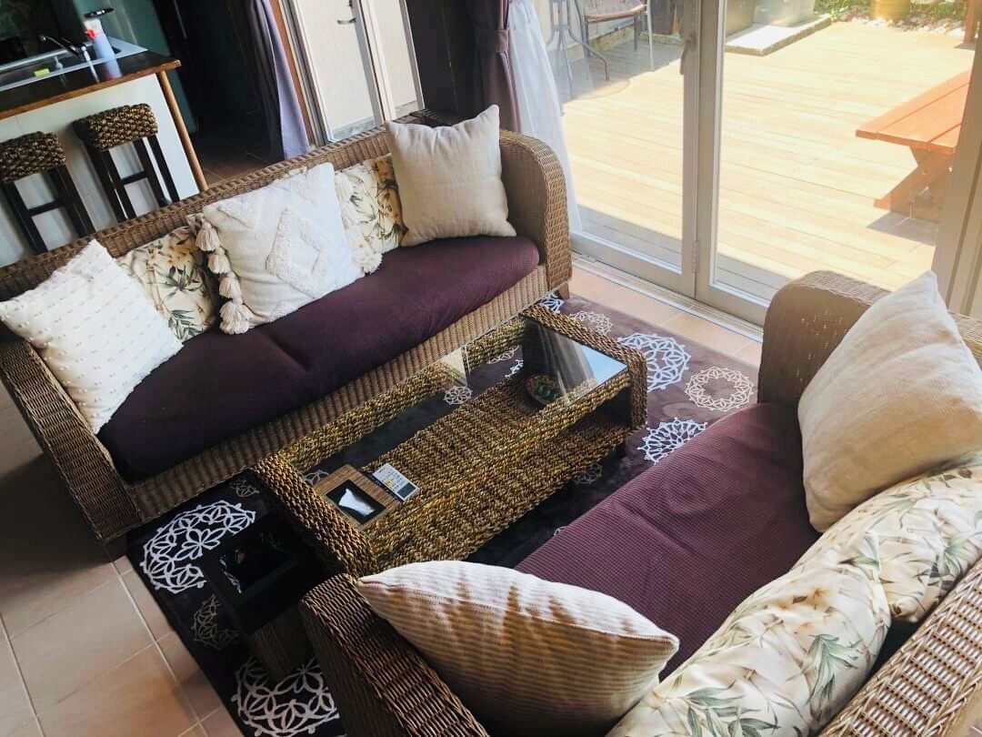 A cozy living room with a sofa set, a coffee table, and a dining area visible through a glass door.