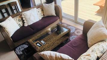 A cozy living room with a sofa set, a coffee table, and a dining area visible through a glass door.