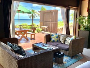 A room with a view of the ocean, featuring wicker furniture, a wooden table, and a bench. - Suite Terrace Ishigakijima (Ishigaki)