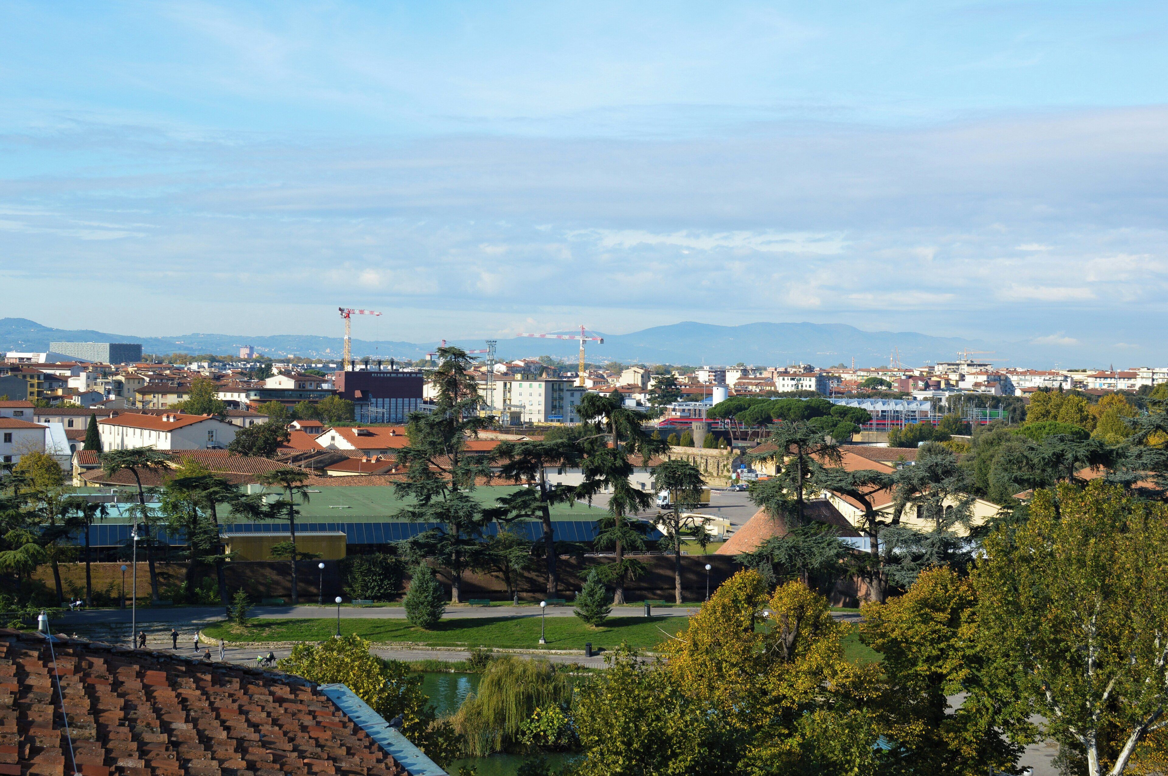 A cityscape with buildings, trees, and a distant mountain range.