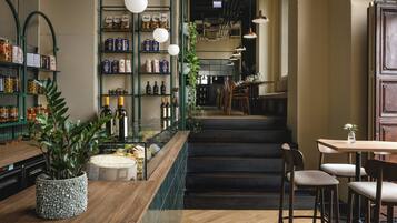 Een restaurant interieur met een bar, houten tafels, stoelen en een trap naar het eetgedeelte.