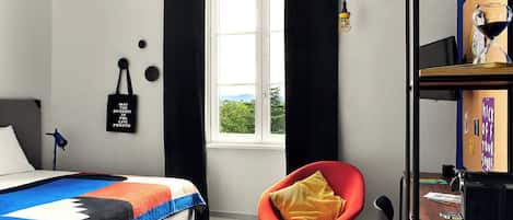 Un dormitorio con cama, una silla, una mesita, una ventana y una pared con una cita motivacional.