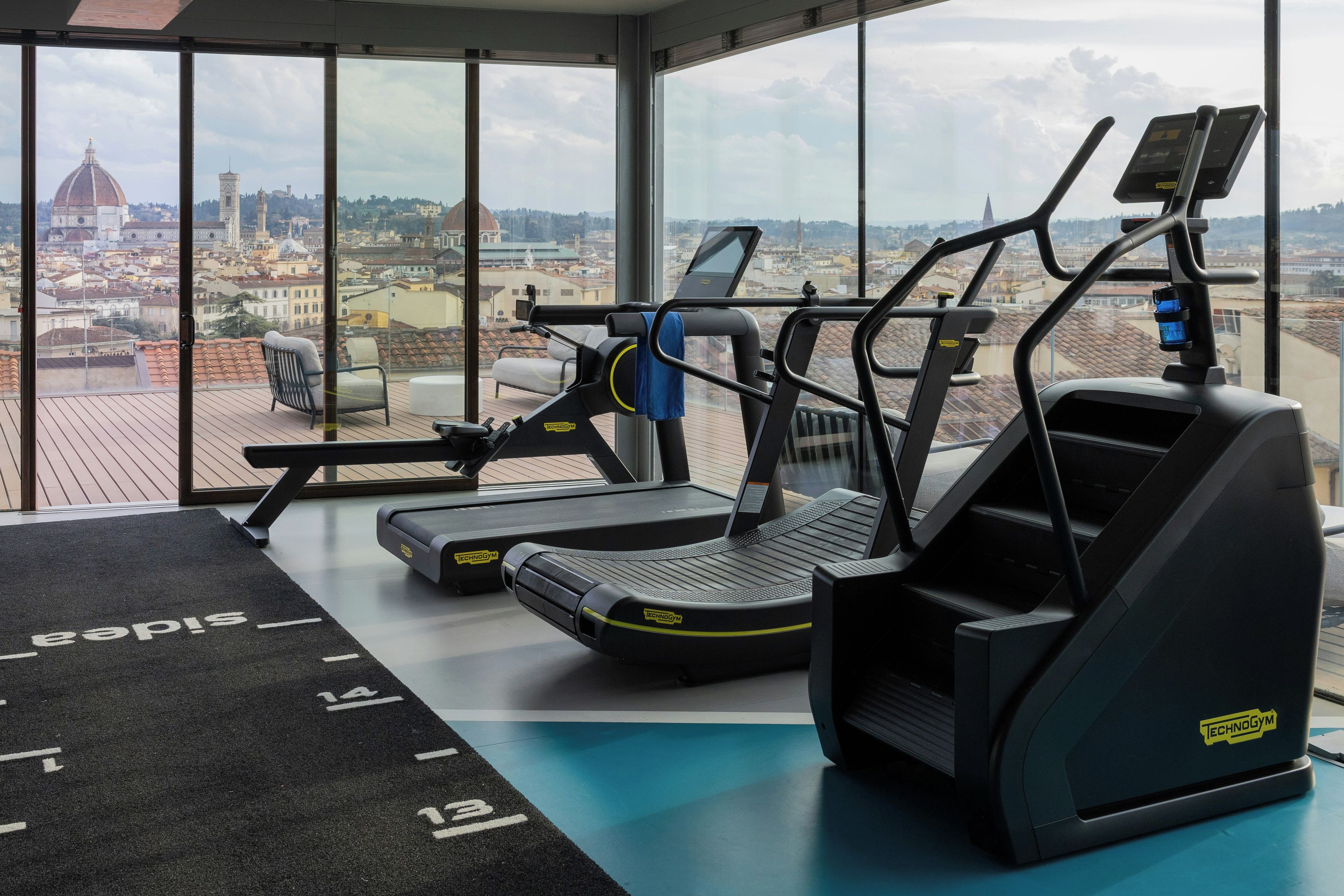A gym with cardio equipment and a view of a cityscape.