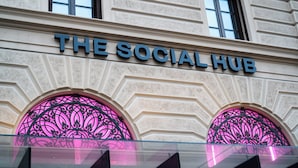 Fachada de edificio con el letrero 'THE SOCIAL HUB' sobre dos ventanas en arco con detalles de hierro forjado.
