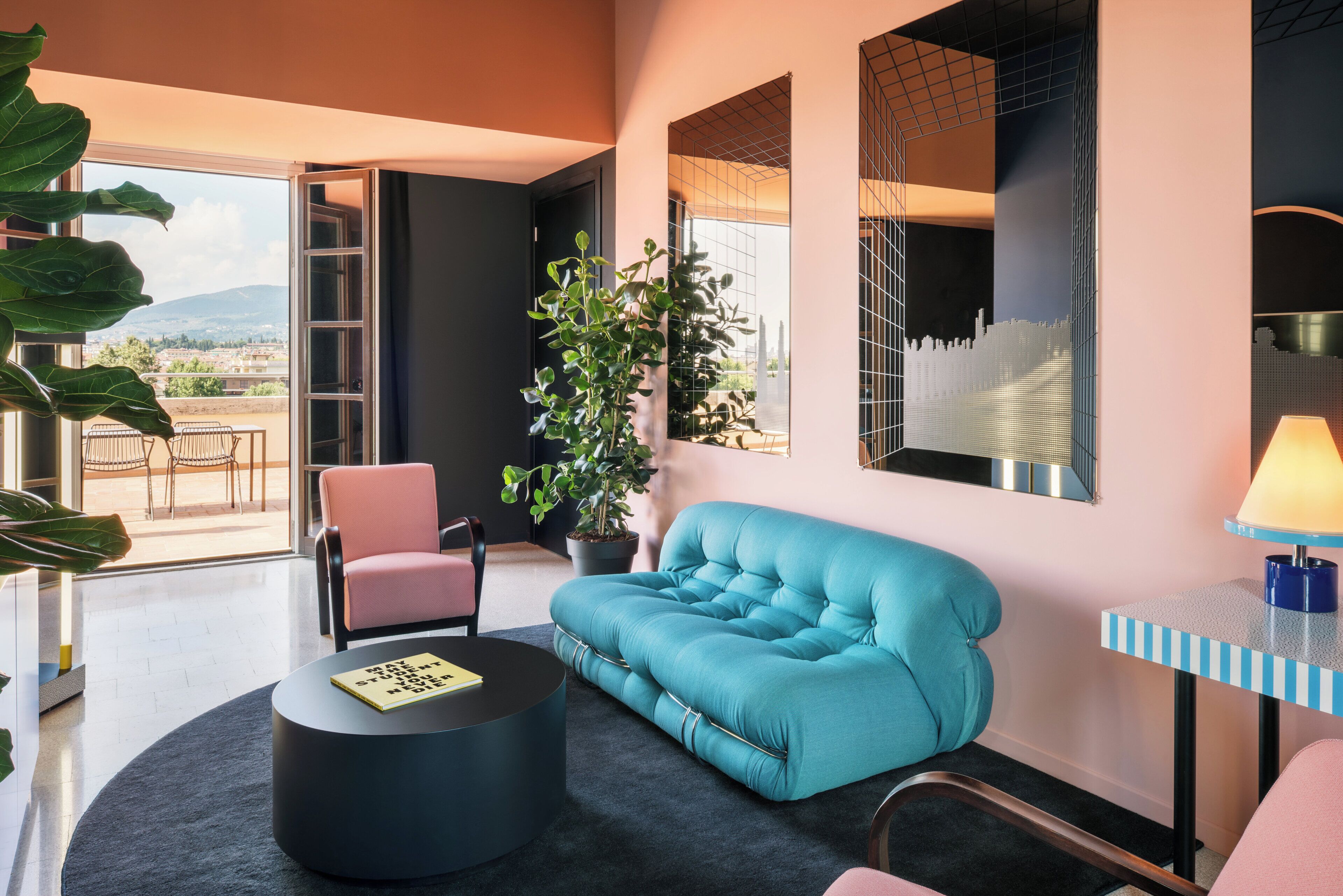 A modern living room with a sofa, a round coffee table, a chair, a potted plant, and a view through a glass door.
