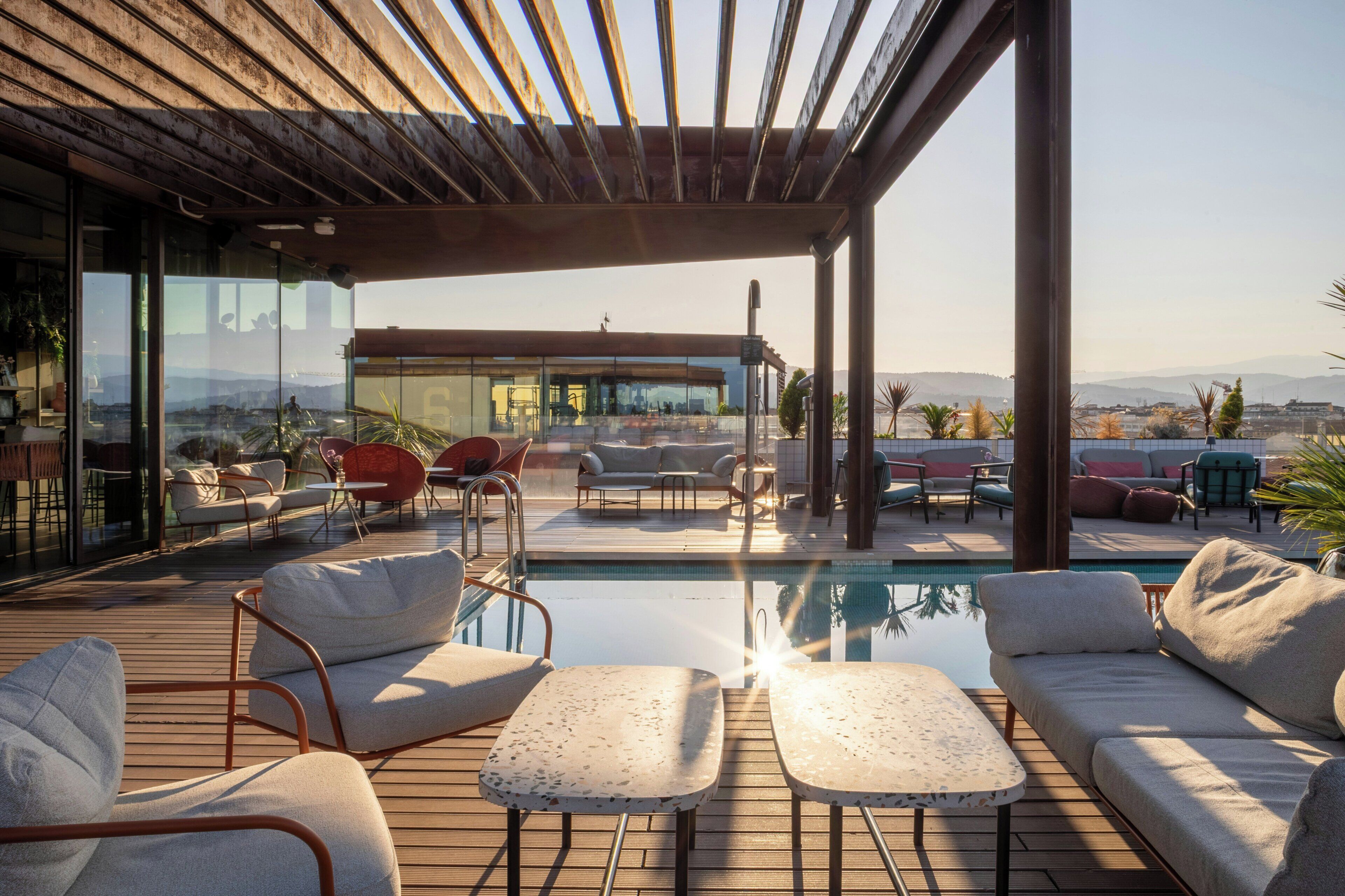 Eine Dachterrasse mit Pool, Sitzgelegenheiten im Freien und Blick auf die Stadt.