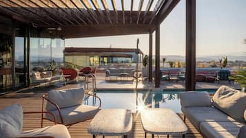Una terraza en la azotea con piscina, mobiliario exterior y vistas a la ciudad.