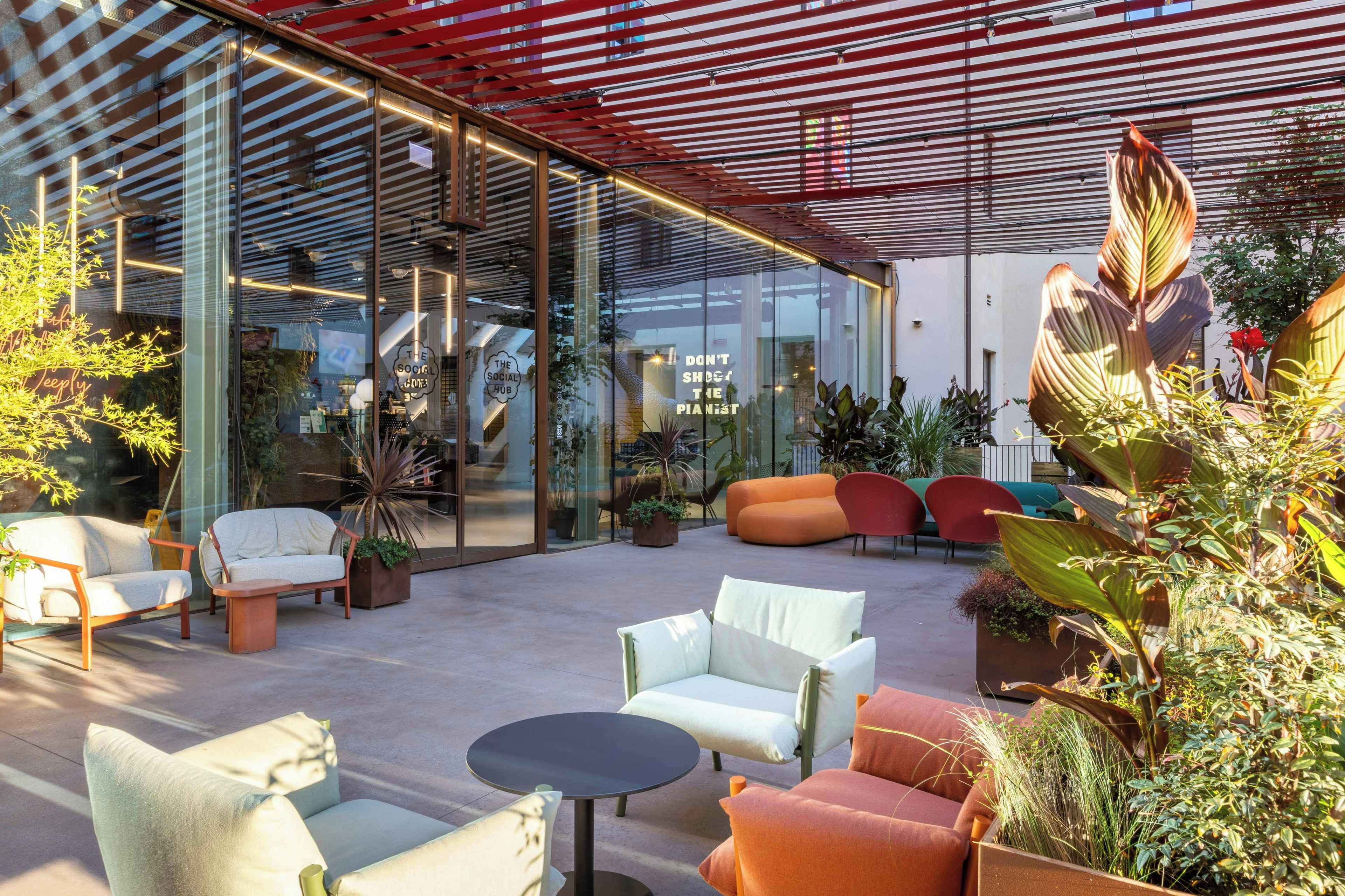Un área de estar al aire libre con muebles modernos y una pared de vidrio.