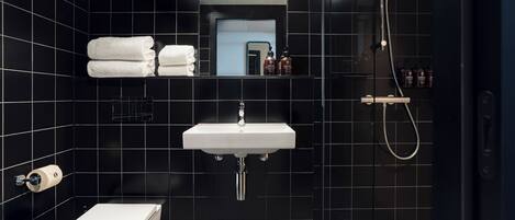 Un baño moderno con lavamanos, inodoro y ducha blancos.