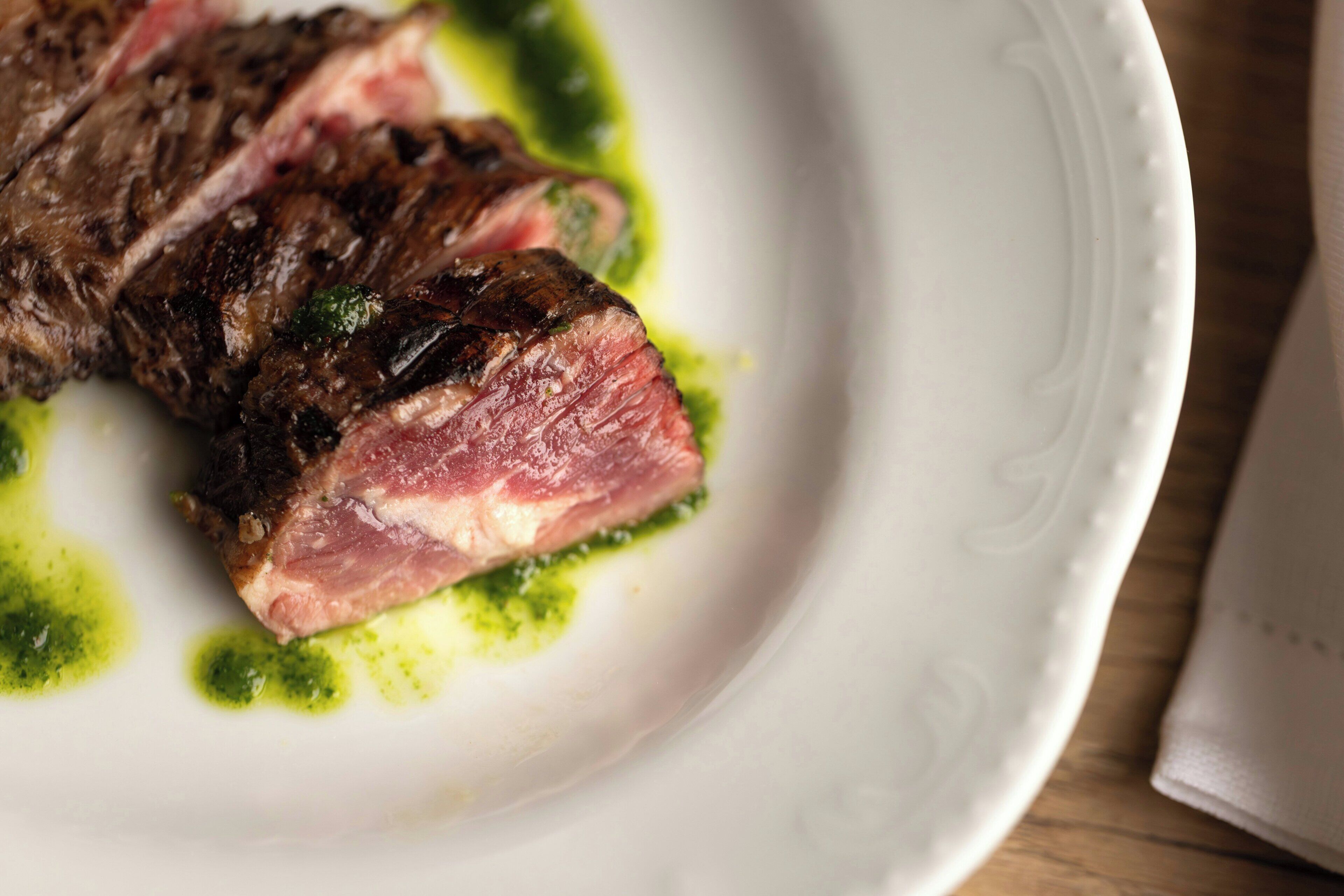 A plate with a grilled steak and a green sauce.