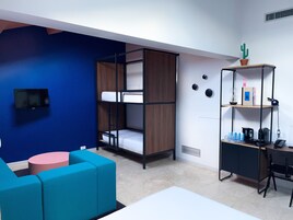 Quarto moderno com beliches, uma escrivaninha, uma cadeira e uma mesinha.