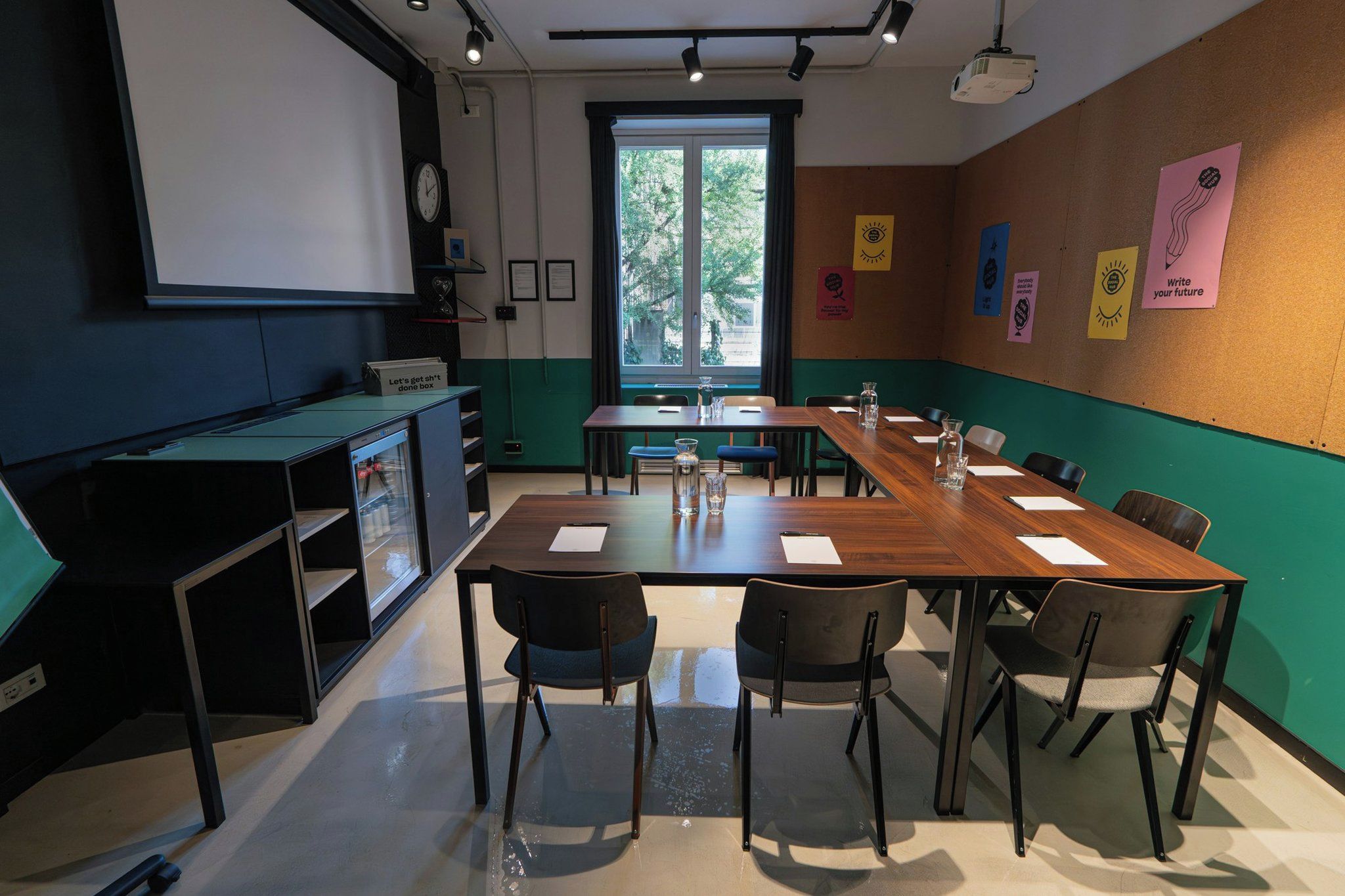 Una sala conferenze con un lungo tavolo, sedie, uno schermo per proiezioni e manifesti motivazionali alle pareti.
